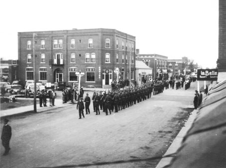 Honour Guard Marching North to train station on 12th Ave. & 5th Street. Empire Hotel in backround.